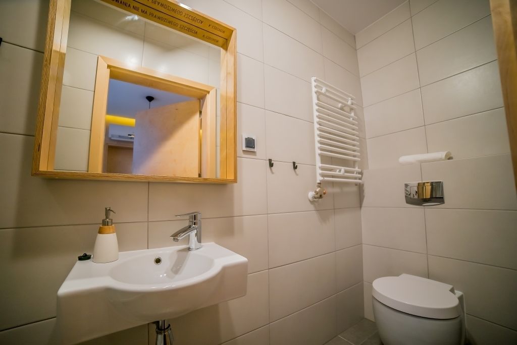 A bathroom with a white sink, a mirror, a toilet, and a towel rack.