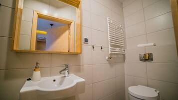 A bathroom with a white sink, a mirror, a toilet, and a towel rack.