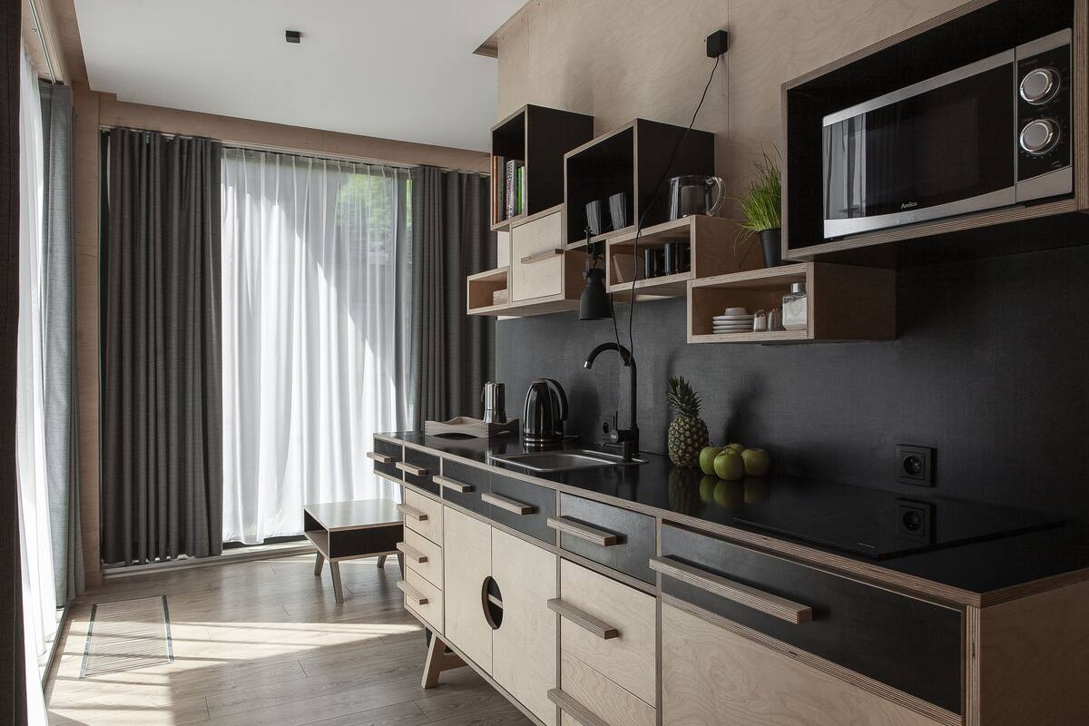 A modern kitchen with a built-in microwave, wooden cabinets, and a large window with curtains.