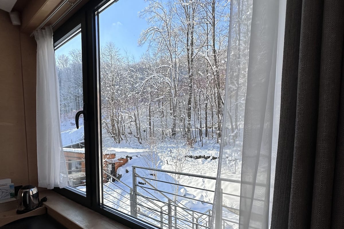 A kitchen with a window overlooking a snowy landscape.