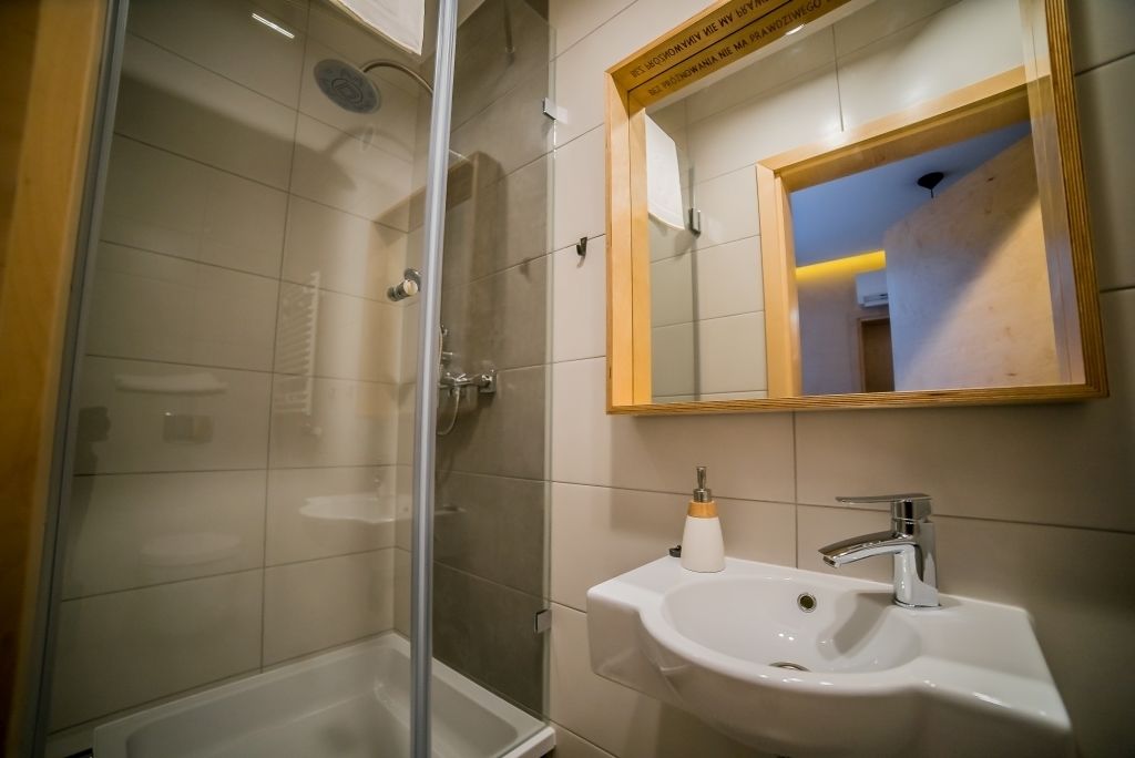 A bathroom with a glass-enclosed shower, a white sink, and a mirror with a wooden frame.
