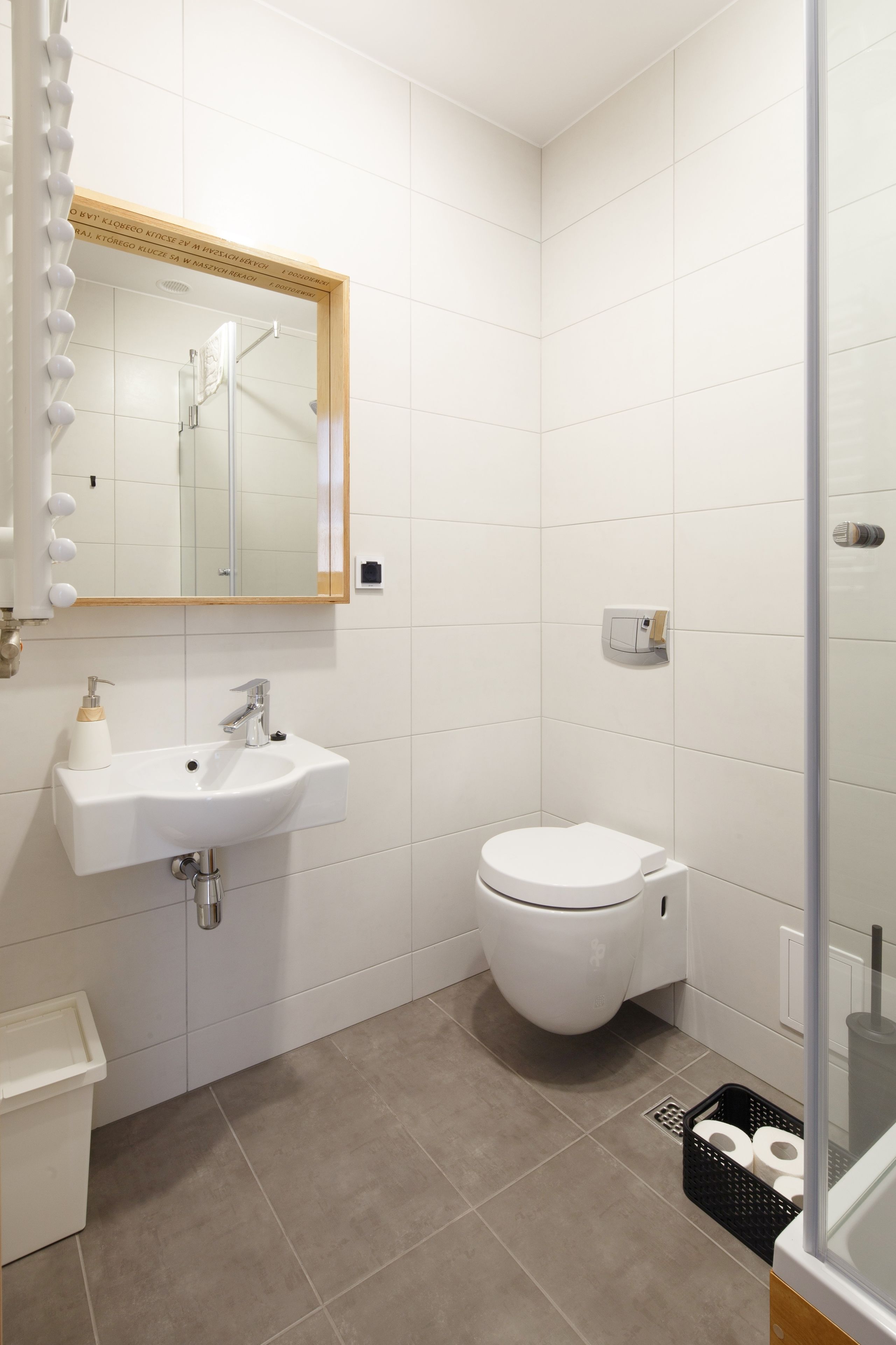 A modern bathroom with a white sink, toilet, and shower.