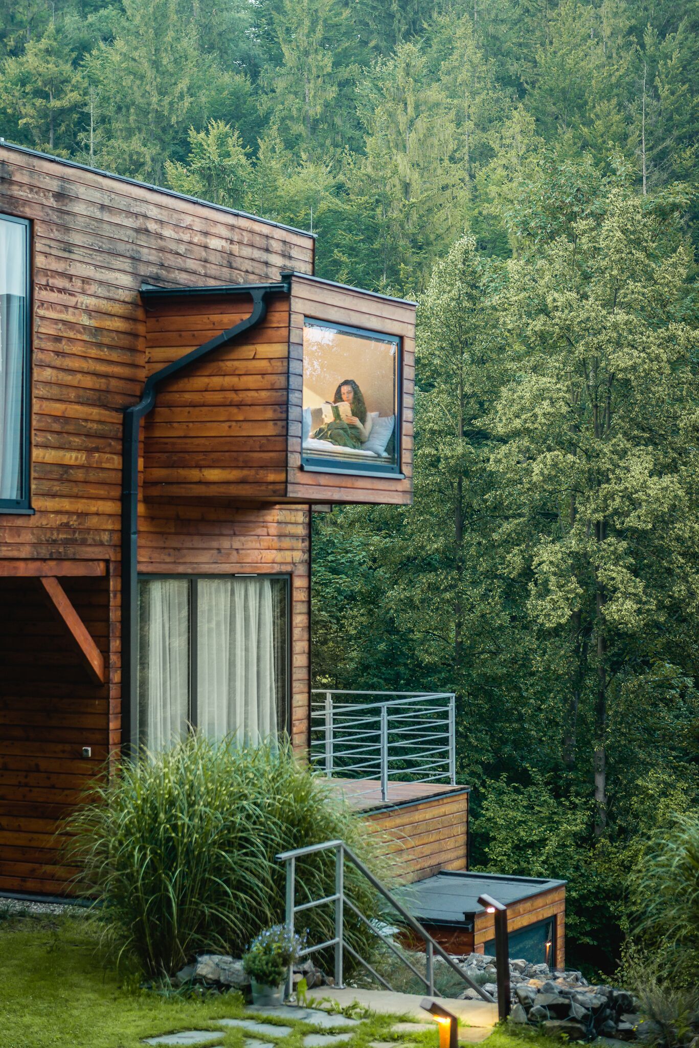 A modern wooden house with a large window and a picture frame on the exterior wall.