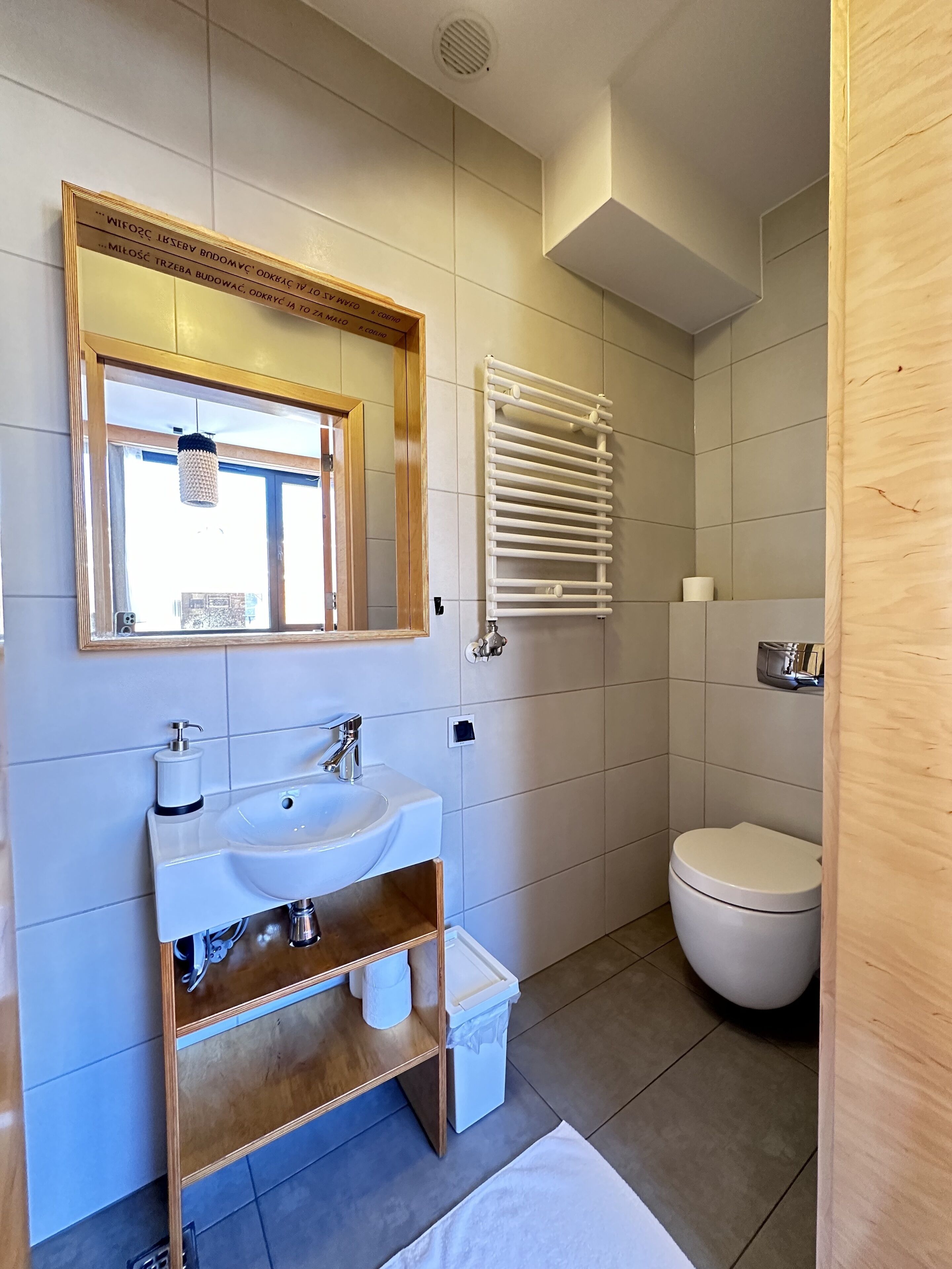 A modern bathroom with a large mirror, white sink, and a toilet.
