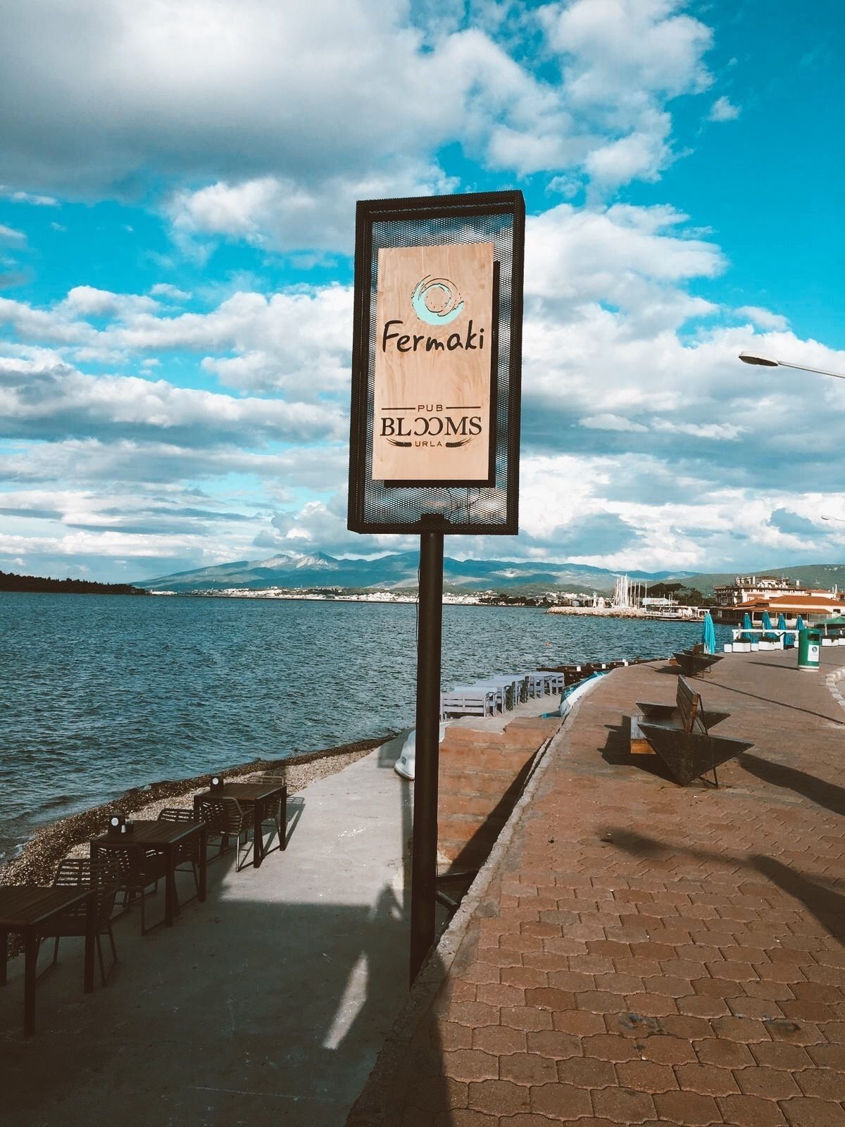 Une vue sur le front de mer avec une enseigne indiquant « Fermaki PUB BLOOMS URLA ».