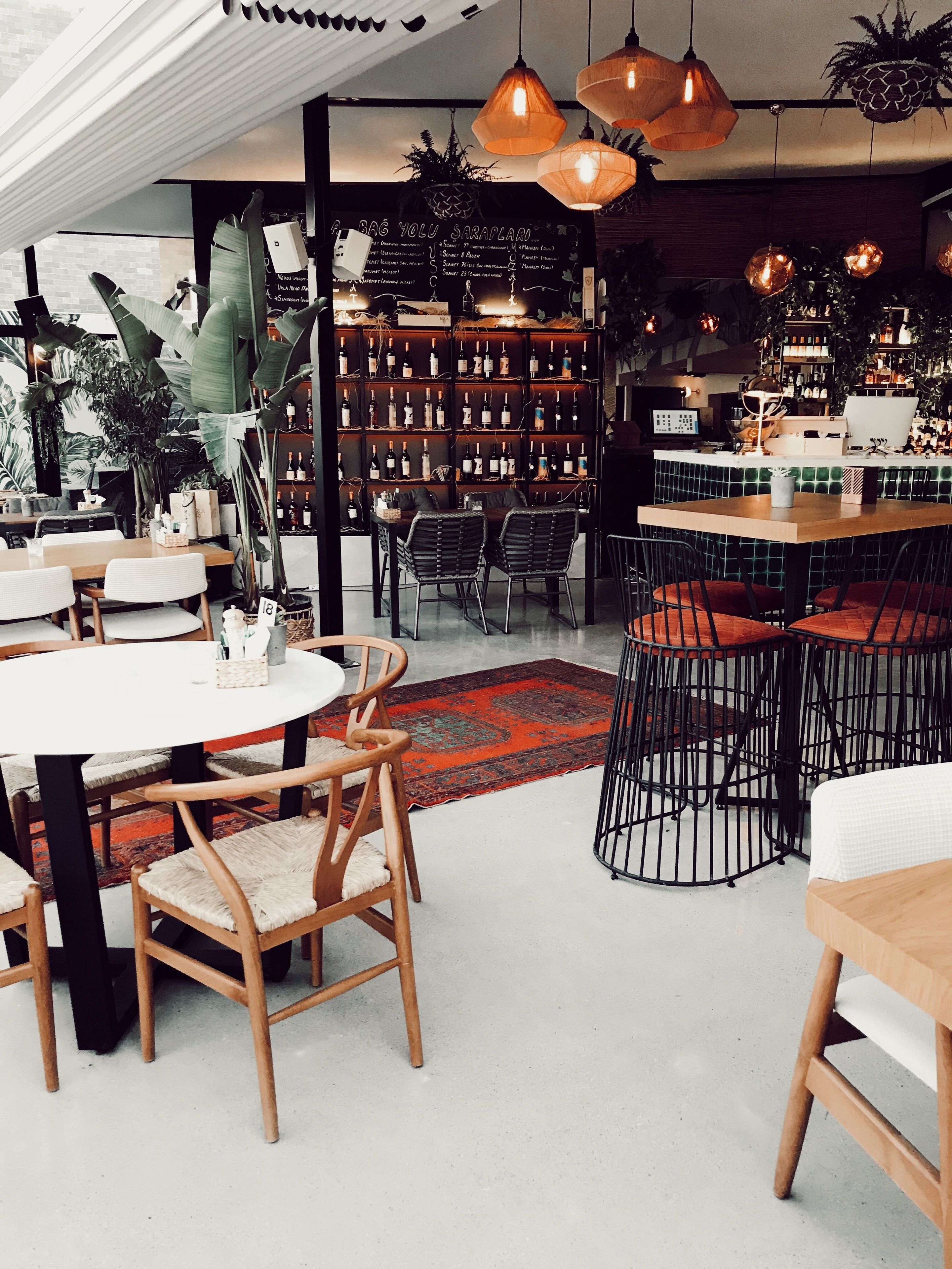 Ein Restaurant mit verschiedenen Sitzgelegenheiten, darunter runde Tische und Stühle, sowie einer Bar mit Regalen voller Flaschen.