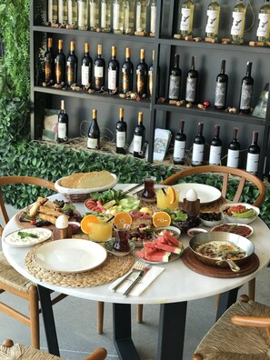 A round dining table with various dishes, glasses, and bottles of wine. - Fermaki Rooms - Adults Only (Urla)