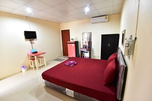 Une chambre d’hôtel comprenant un lit, un bureau, une chaise, une télévision, une armoire et une salle de bain.