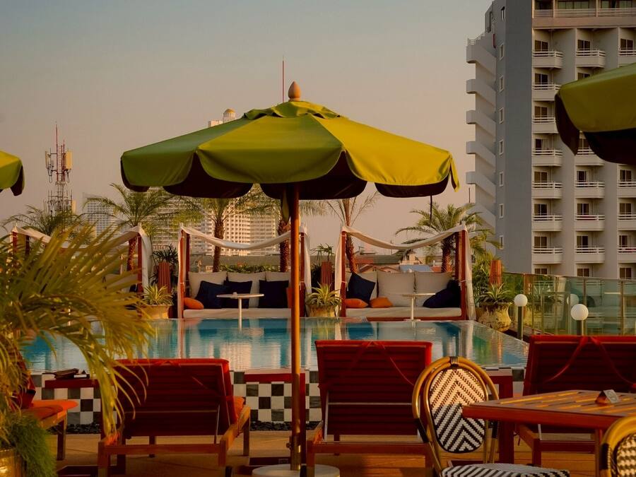 A poolside area with lounge chairs, umbrellas, and a pool.