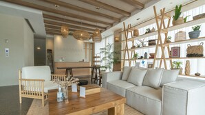 A modern living room with a wooden coffee table, a grey sofa, and a wooden ladder shelf with plants. - Tribe Pattaya (Pattaya)