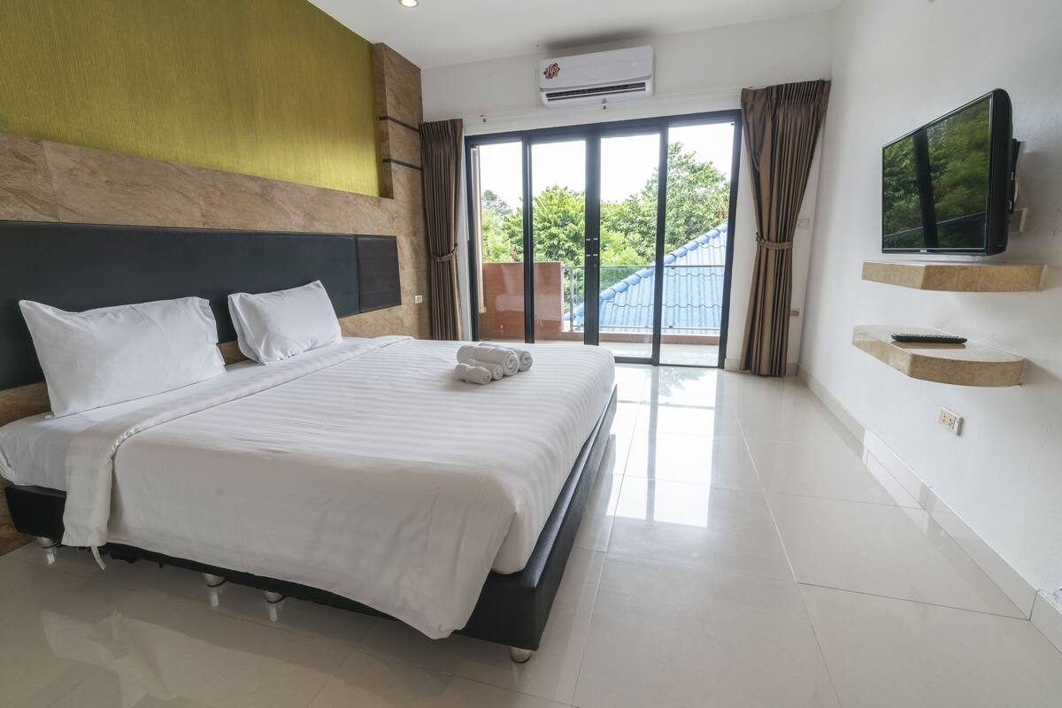 Hotelkamer met een groot bed, een flatscreen televisie aan de muur bevestigd en een schuifdeur naar buiten.