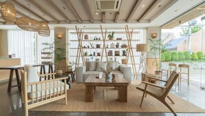A modern interior with a sofa, coffee table, wicker chairs, and a shelving unit with plants. - Tribe Pattaya (Pattaya)