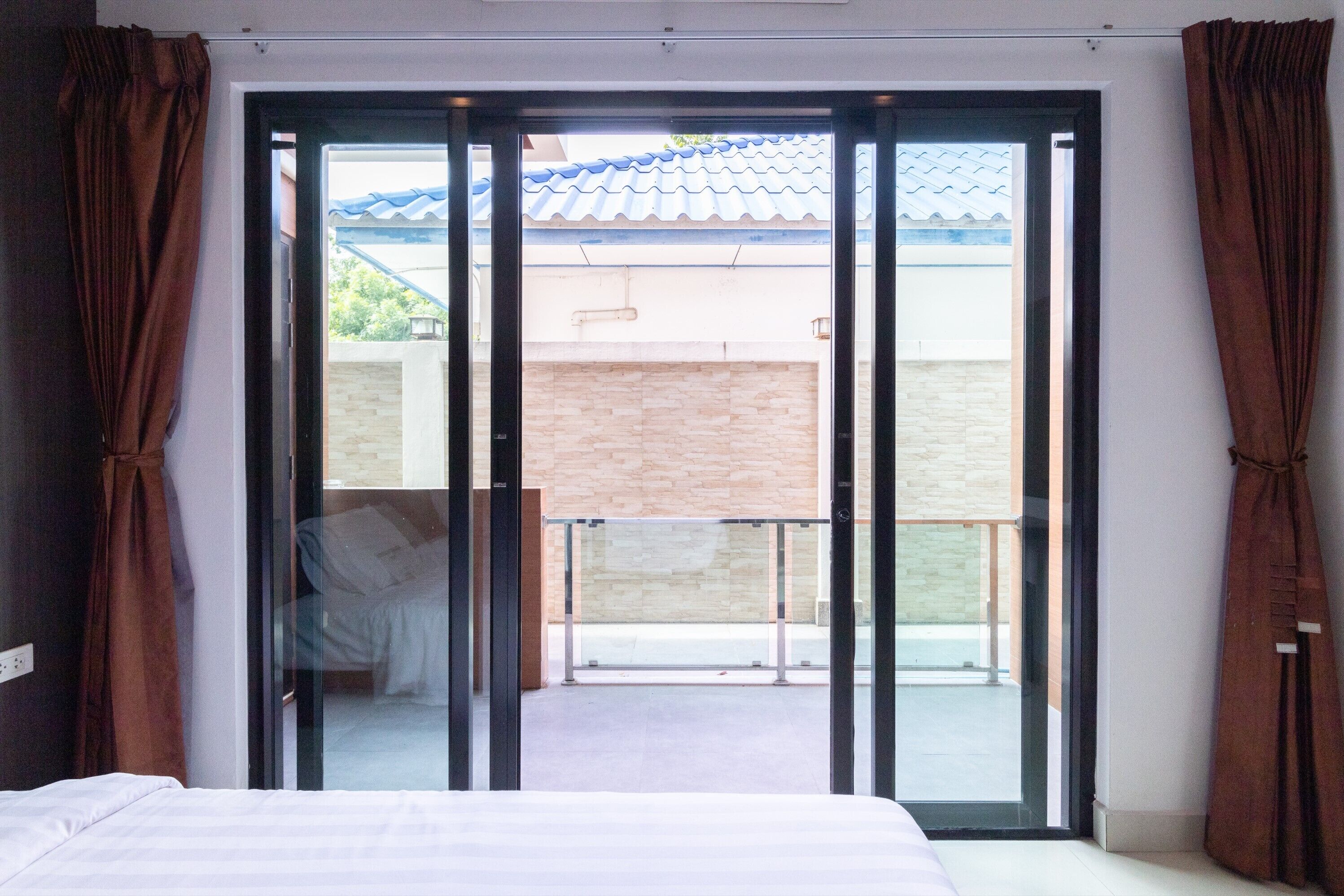 A bedroom with a large sliding glass door leading to a balcony.