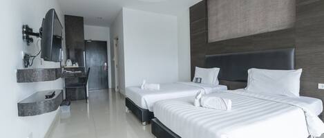 Ein modernes Hotelzimmer mit zwei Betten, einem integrierten Fernseher, einem Badezimmer mit Spiegel und einem großen Fenster.