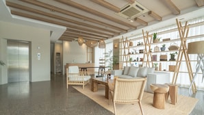 A spacious lobby with a high ceiling, wooden beams, a reception desk, seating area, and a plant-filled shelving unit. - Tribe Pattaya (Pattaya)