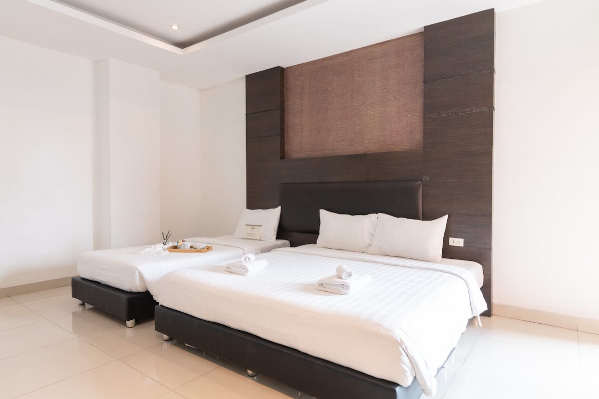Een moderne hotelkamer met twee bedden, een donker hoofdbord en een strak, minimalistisch design.