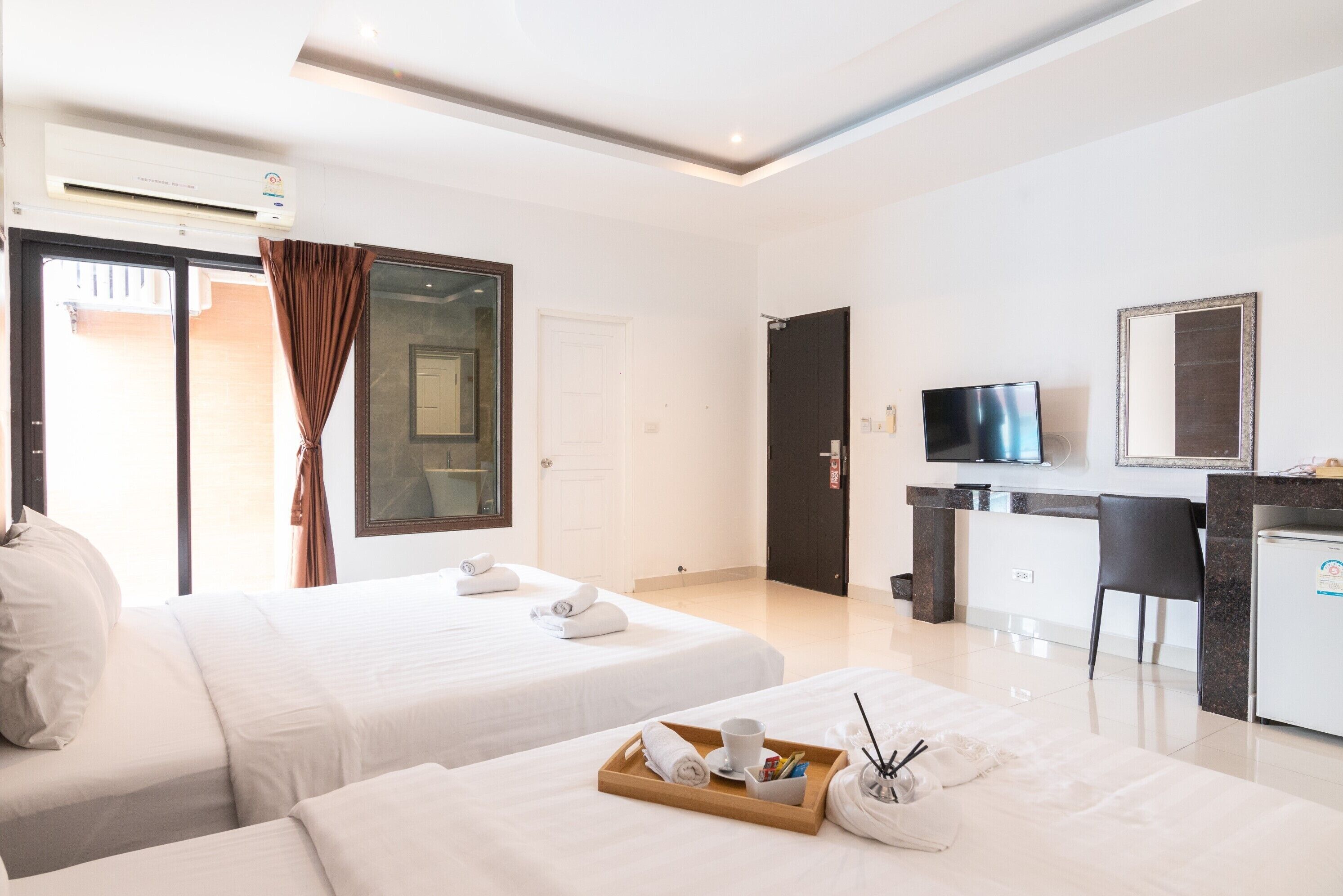 A hotel room with two beds, a TV, a desk, and a minibar.