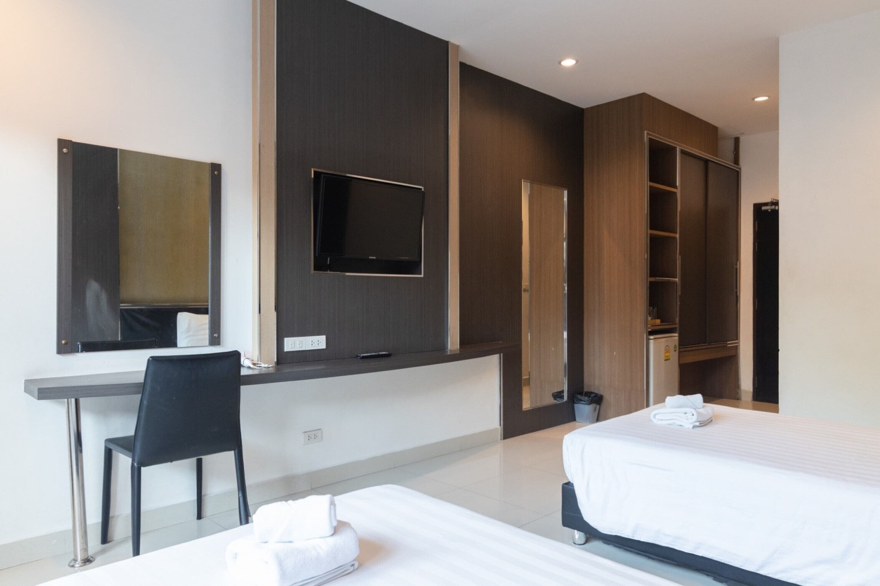A modern hotel room with a desk, two beds, a TV, and a wardrobe.