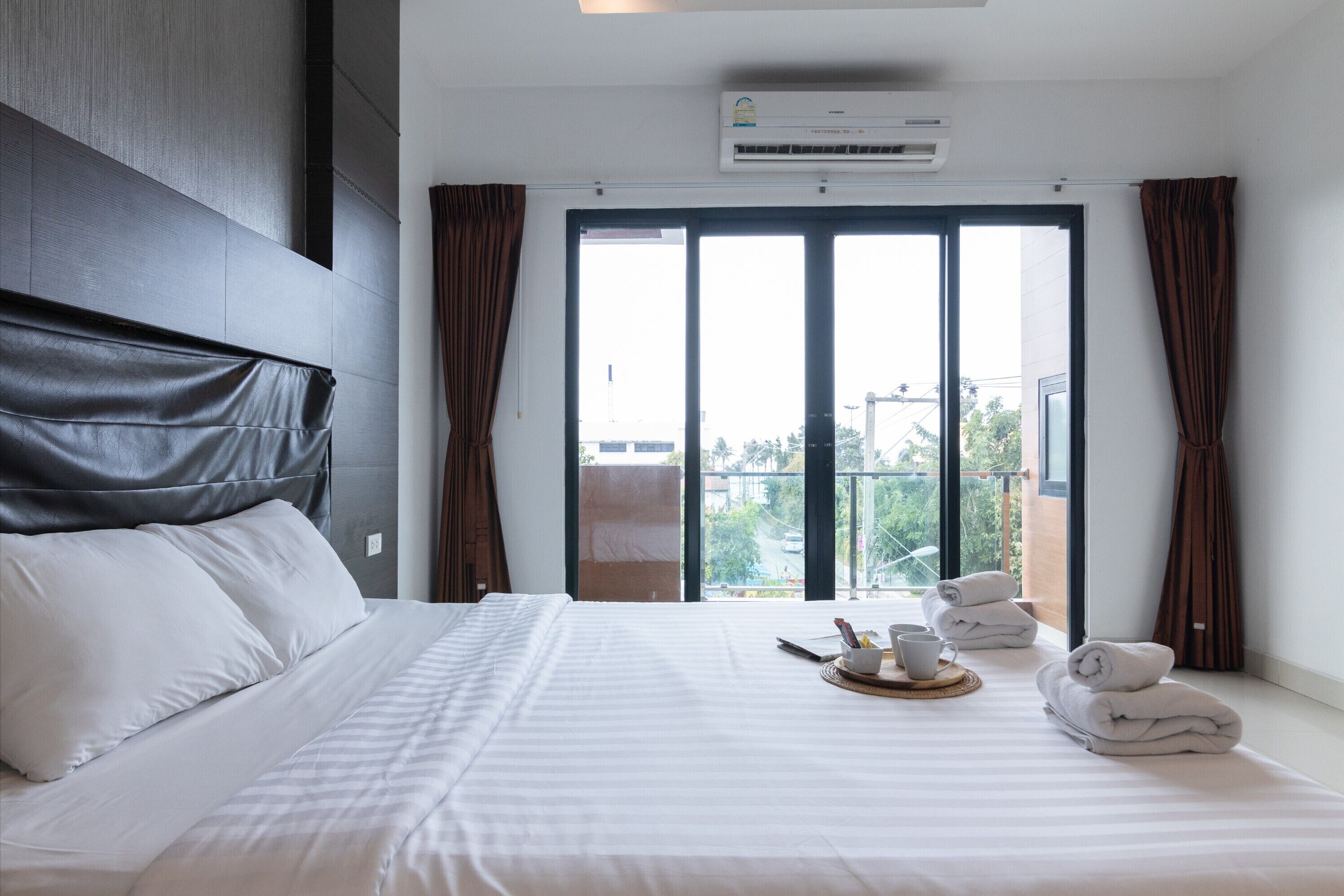 Ein Hotelzimmer mit einem großen Bett, Blick ins Freie und einer Klimaanlage.
