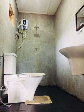 Un baño pequeño con inodoro, lavamanos y ducha.