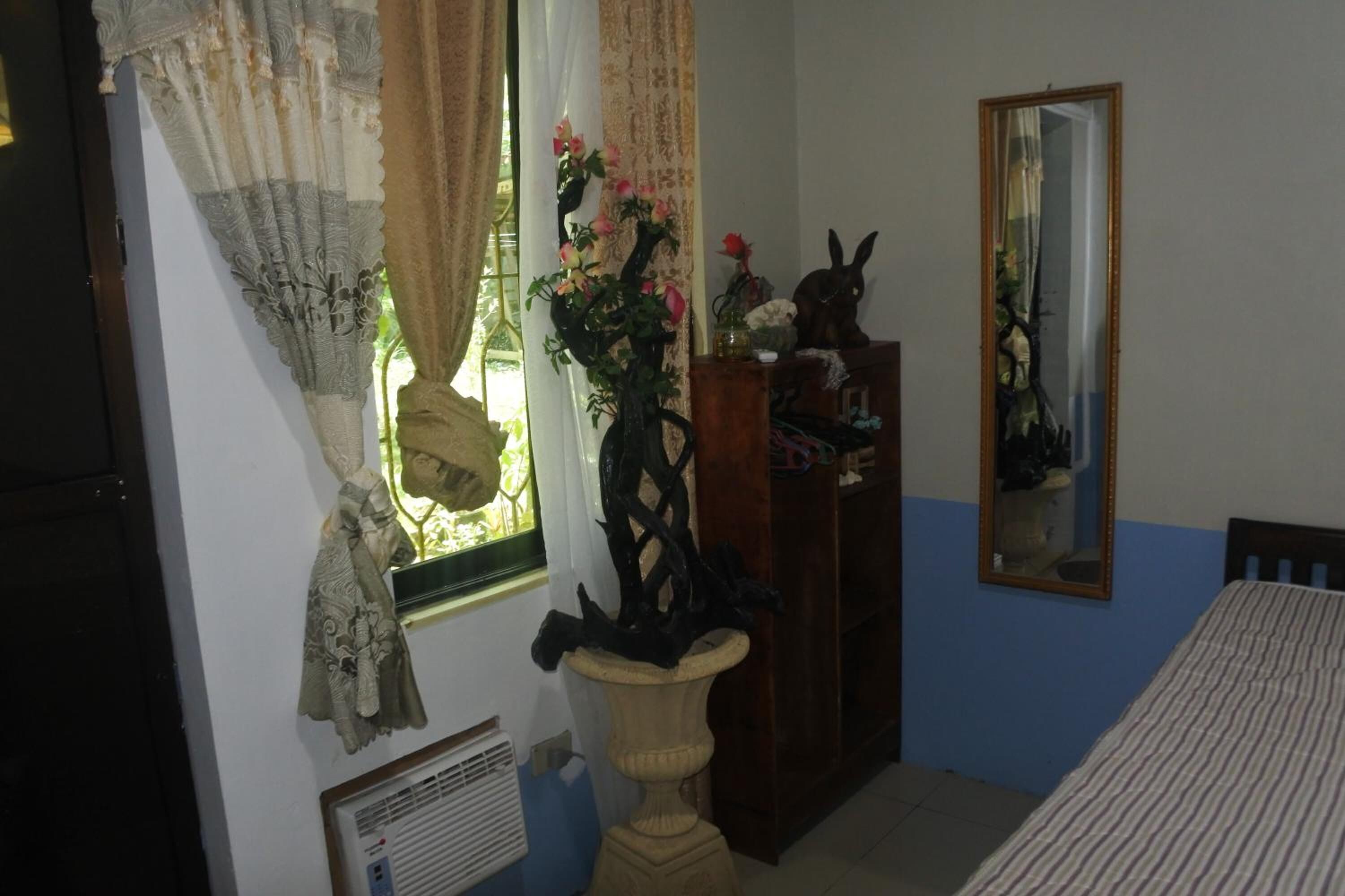 A bedroom with a bed, a dresser, a mirror, and a window with curtains.