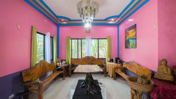 A room with a wooden table, benches, a Buddha statue, and a chandelier.