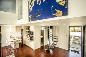 Spacious living area with a mezzanine level, kitchen, dining space, and glass door leading to the outdoors.