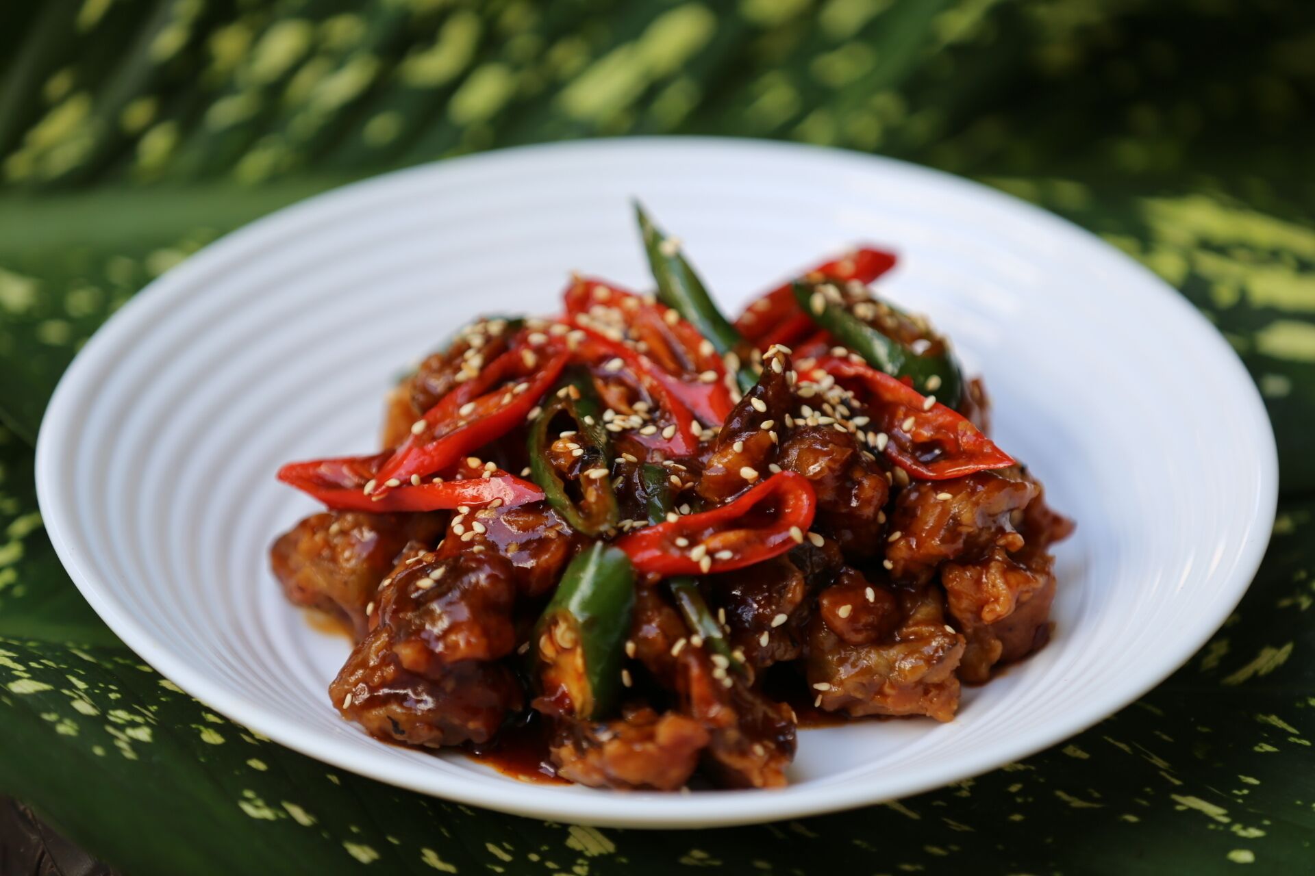 A plate of food with red peppers and sesame seeds.