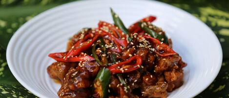 A plate of food with red peppers and sesame seeds.
