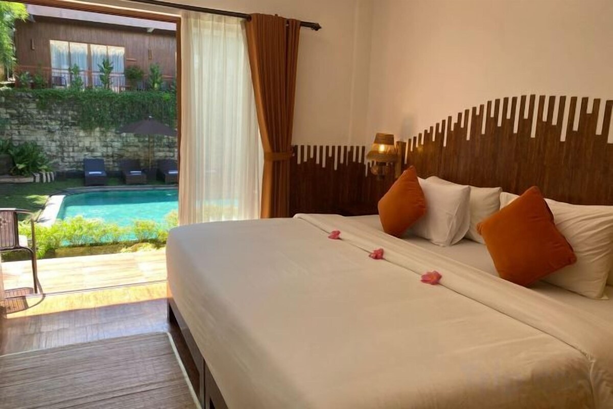 A hotel room with a bed, a view of a swimming pool, and a balcony.