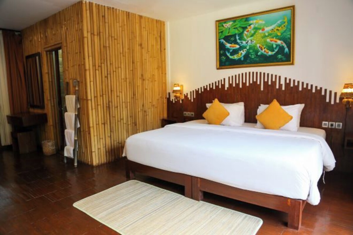 A hotel room with a bed, a wooden wall, a painting, and a nightstand.