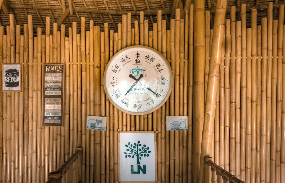 A bamboo wall with a clock and various signs, including one for 'LN'.