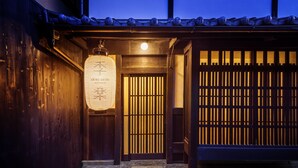Un edificio japonés tradicional con fachada de madera, techo de tejas y un farol iluminado.