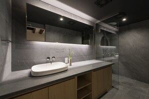 Un baño moderno con un espejo grande, un lavabo integrado y una zona de ducha.