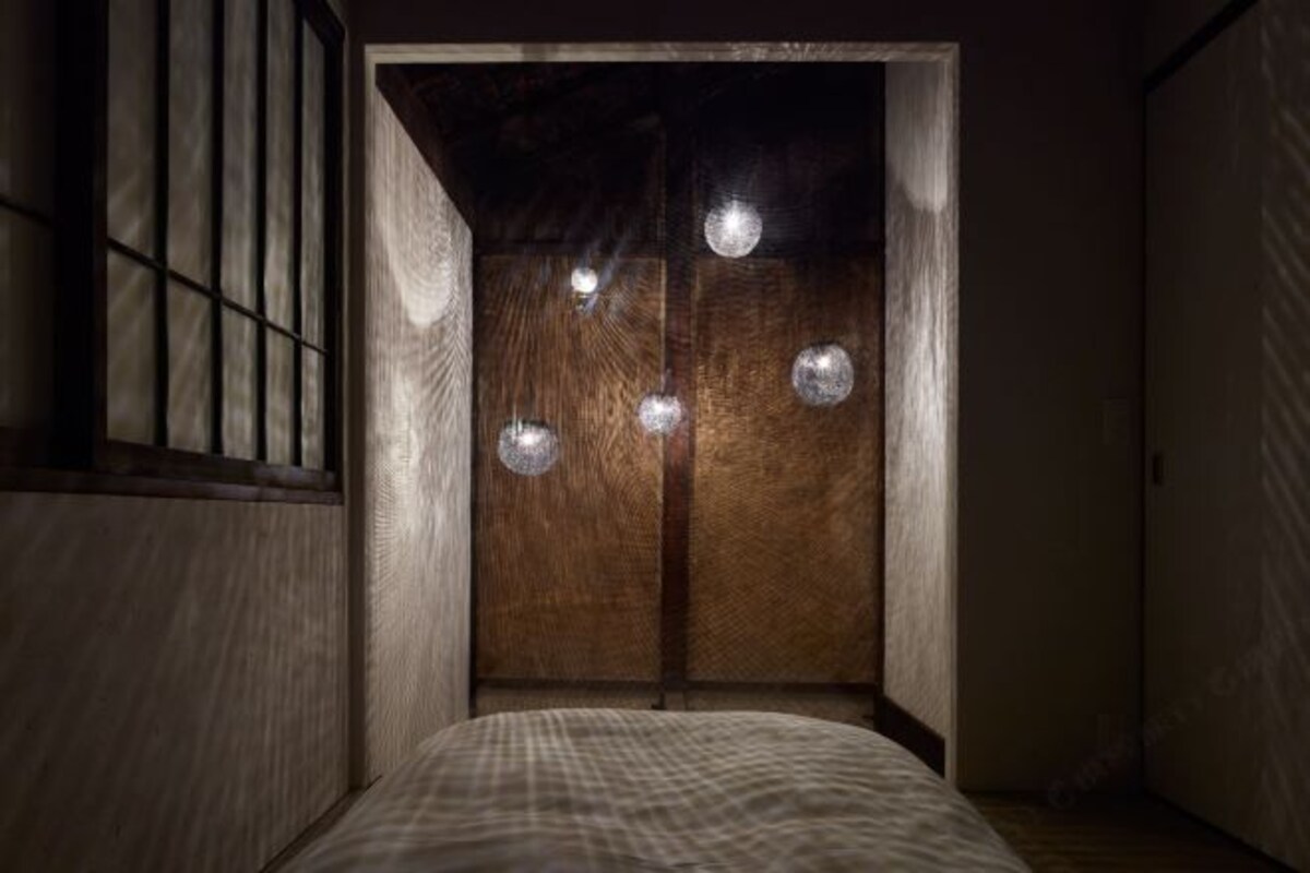 A room with a bed, wooden walls, and a window with vertical bars.