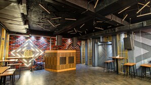 Un intérieur moderne avec des plafonds apparents, un mur de briques orné d'une enseigne au néon et un comptoir central en bois.