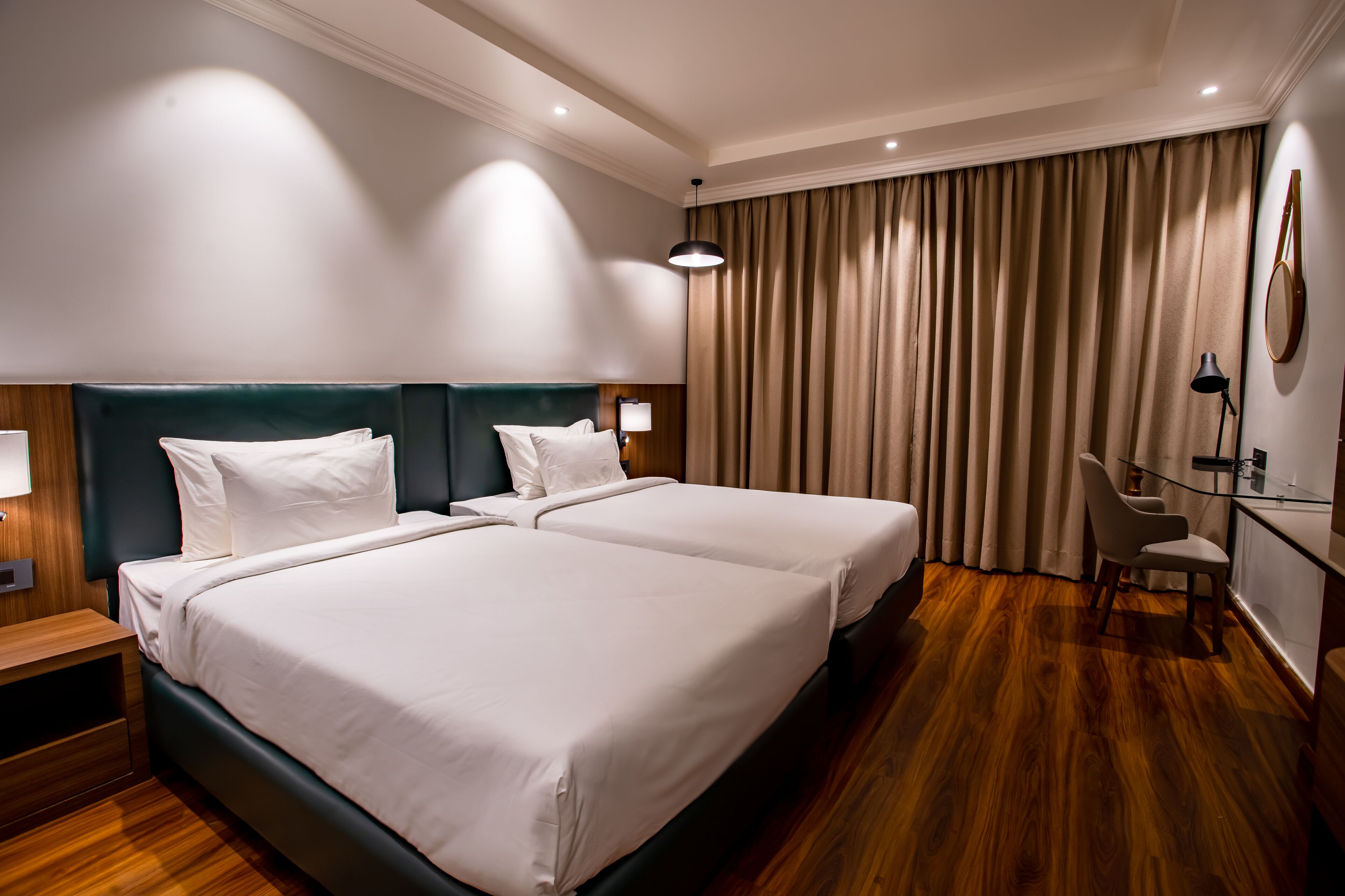 A hotel room with two beds, a desk, and a chair.