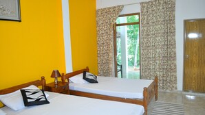 A room with two wooden beds, a wooden door, and a view of greenery outside. - Dil Lanka Safari Resort (Udawalawa)