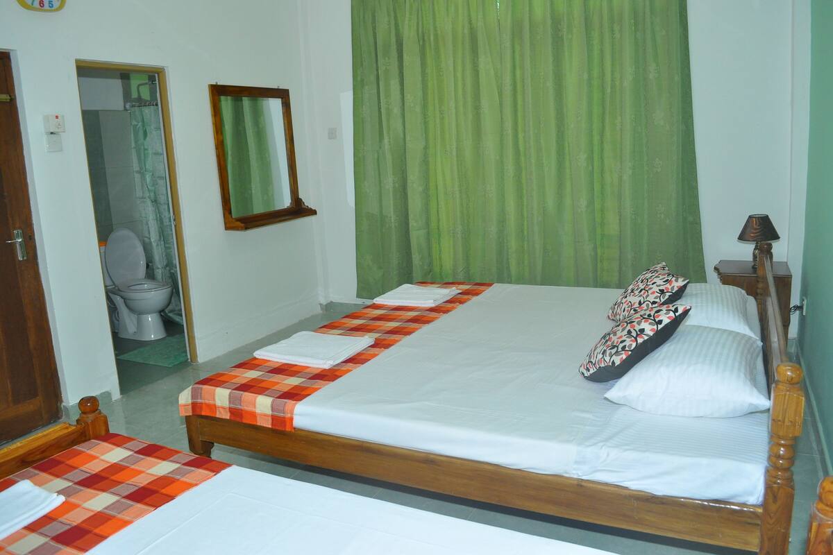 Un dormitorio con una cama grande, un cabecero de madera y una cortina verde.