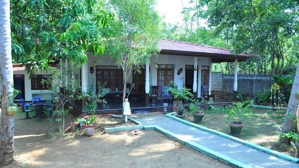 A house with a porch, potted plants, and outdoor seating. - Dil Lanka Safari Resort (Udawalawa)
