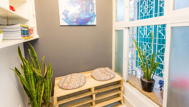 Een hoekje met een houten bankje, een plant in pot en een raam met decoratief glas.