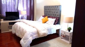 Une chambre à coucher bien rangée, avec un lit, une télévision, une table de chevet avec une lampe et une petite plante.