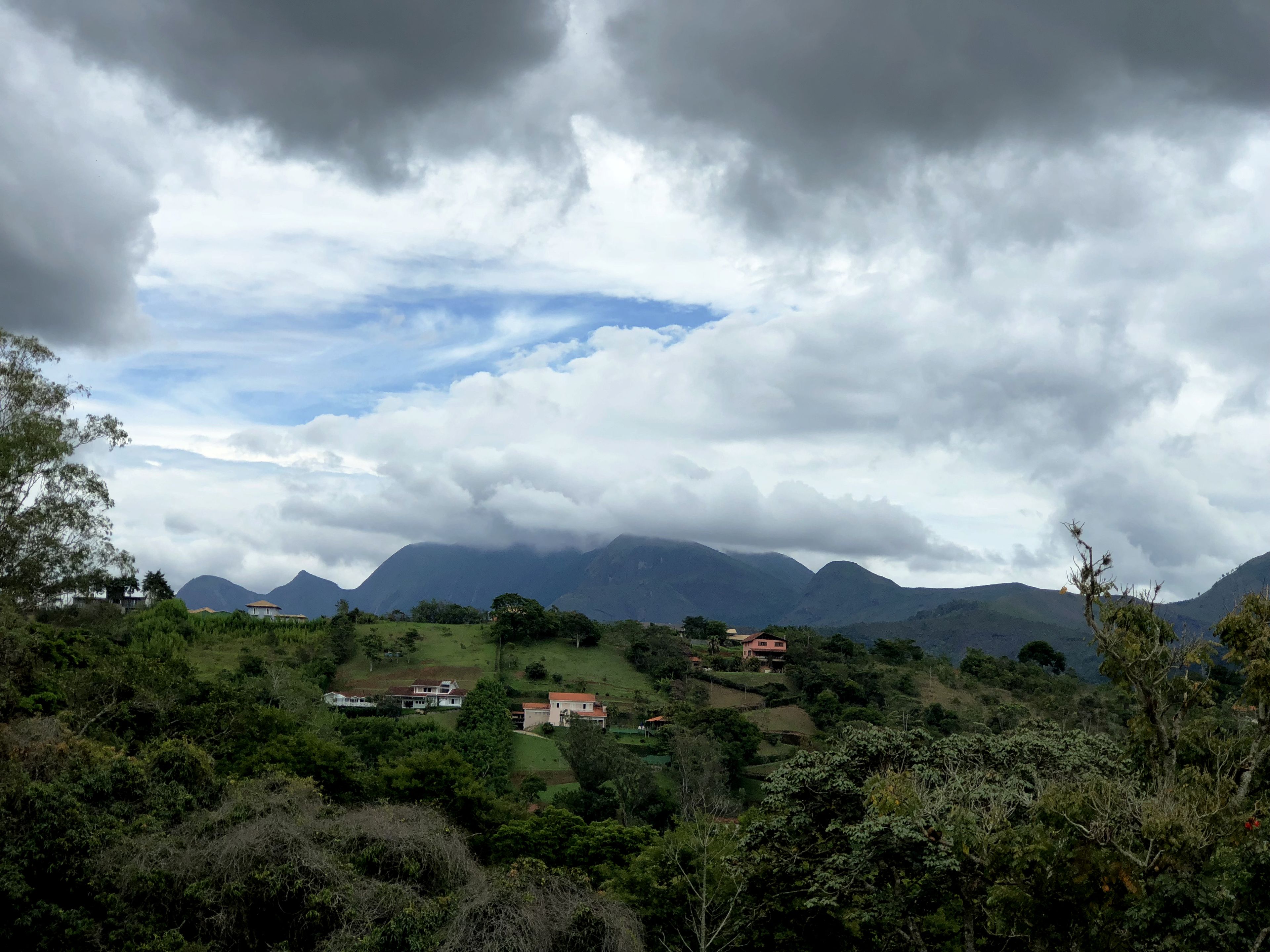 Un paysage montagneux parsemé de maisons et d’une végétation luxuriante.