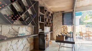 A modern interior with a stone wall, wine racks, a small refrigerator, and a view of the outdoors. - Pousada Golf Village (Petrópolis)