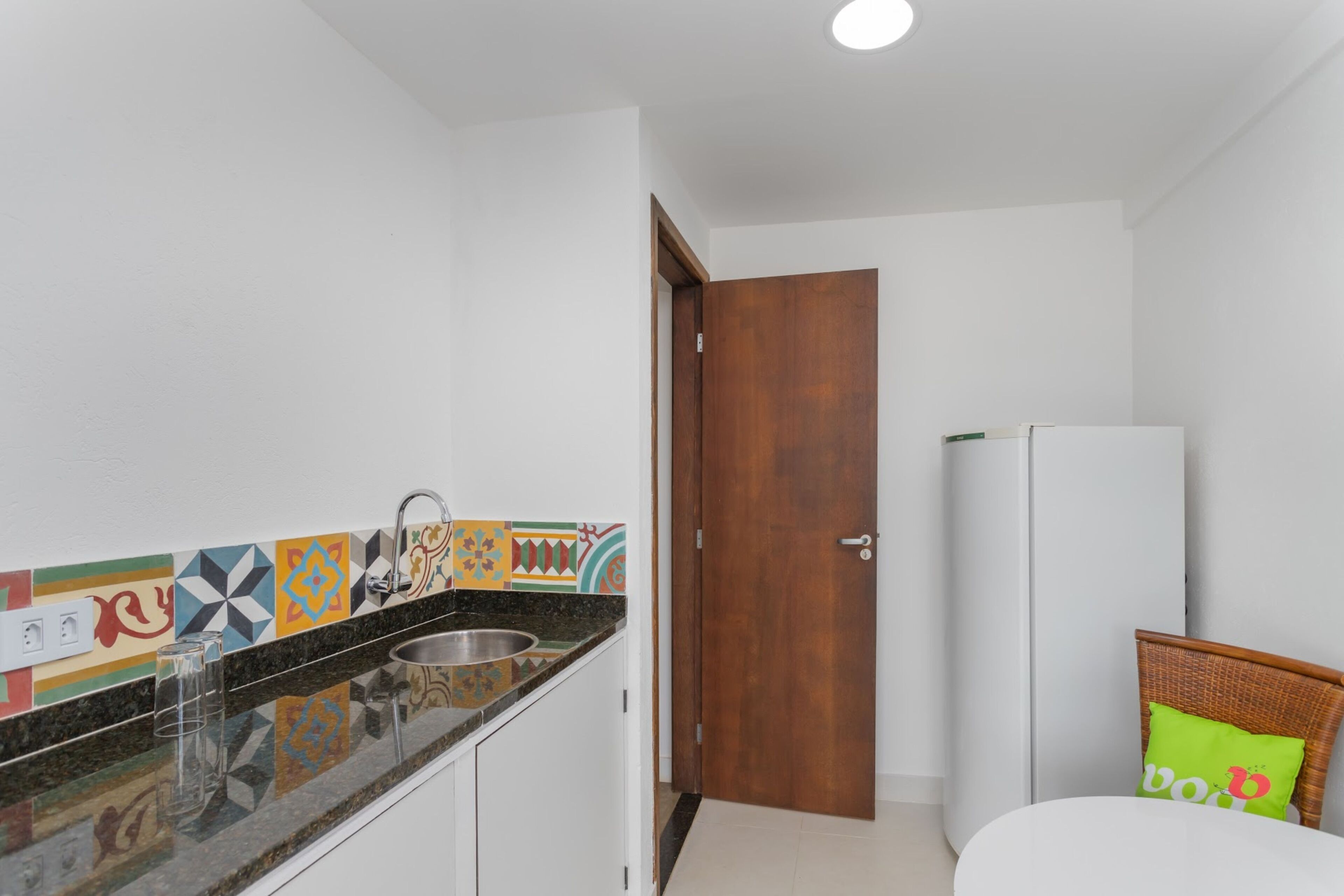 A kitchen with a sink, a wooden door, and a white refrigerator.