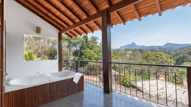 A modern bathroom with a large bathtub, wooden paneling, and a view of the surrounding landscape. - Pousada Golf Village (Petrópolis)