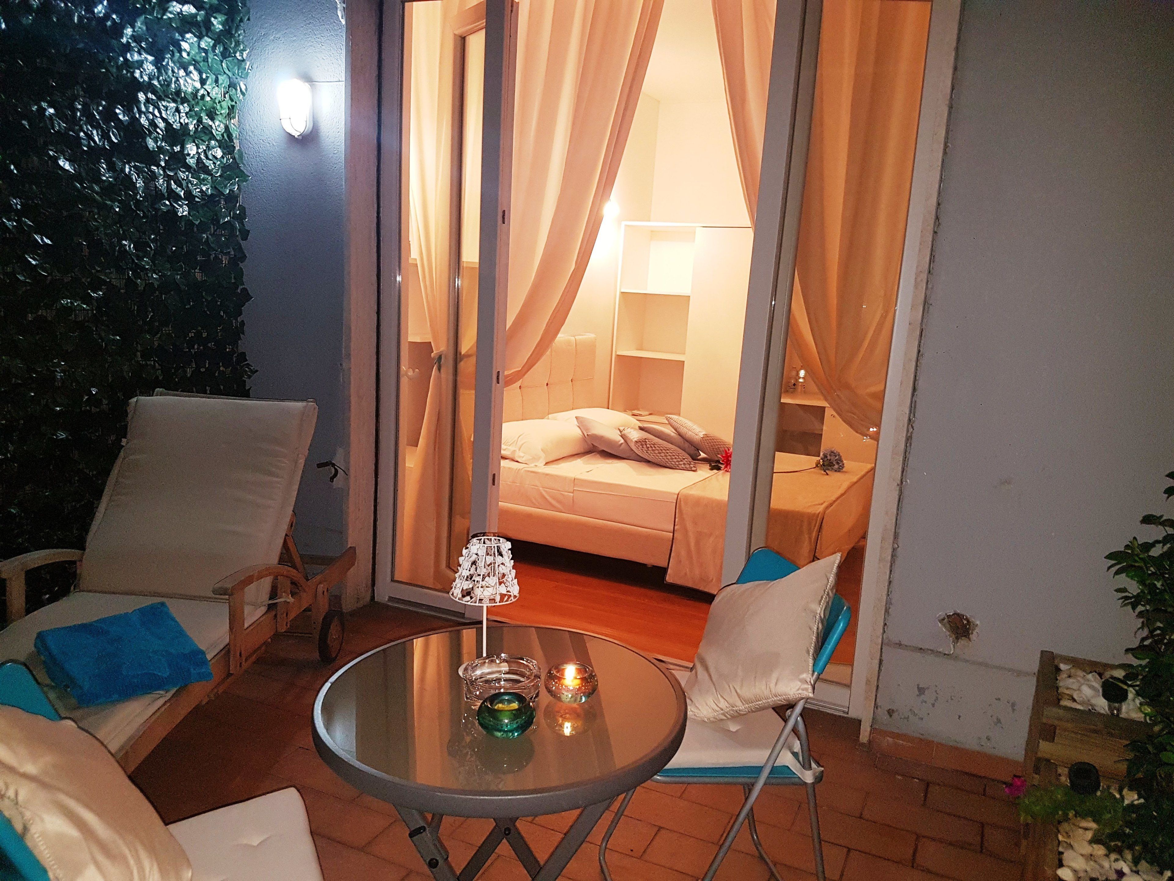 Un espace extérieur accueillant avec une table en verre, deux chaises et une petite table décorée de bougies.