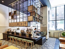 A modern bar area with a central counter, stools, and a unique geometric shelving structure.