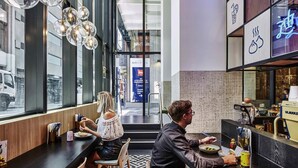 Un intérieur moderne avec un bar, des sièges et une vue sur la rue.