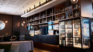 Un espace bar avec des étagères remplies de bouteilles, un comptoir et des sièges.